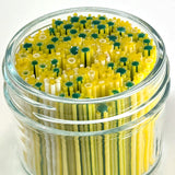 A glass jar filled with yellow and green straws, creating a colorful and playful arrangement.