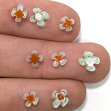 a close-up view of a person's fingers adorned with small, colorful flower-shaped objects made of glass or plastic.