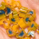 a close-up view of a collection of colorful, flower-shaped objects made of yellow and blue glass beads.