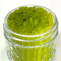 A glass jar filled with green, elongated objects, possibly a type of candy or a similar treat.