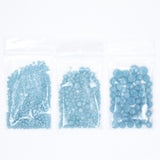 Three transparent plastic bags filled with small, light blue beads are arranged in a row.