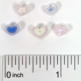 a collection of heart-shaped beads, each varying in size, placed next to a ruler for scale.