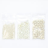 three transparent plastic bags filled with white beads or small white objects, arranged in a row.