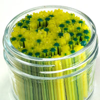 A glass jar filled with yellow and green toothpicks arranged in a circular pattern.