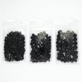 Three transparent plastic bags filled with black beads are arranged in a row.