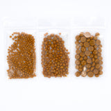 three transparent plastic bags filled with small, round objects, likely beads or nuts, arranged in a row.