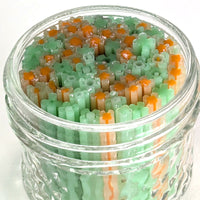 A glass jar filled with colorful, multicolored flower-shaped objects, including green and orange elements.