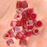 a collection of small, red and white candy pieces scattered on a person's hand.