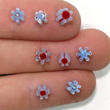 a close-up view of a person's fingers adorned with small, colorful flower-shaped objects made of plastic.