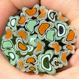 A close-up image of a hand holding a collection of colorful, abstract glass or ceramic shapes resembling flowers or leaves.