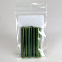 A clear plastic bag containing a group of green, cylindrical objects, which appear to be candles or similar items.