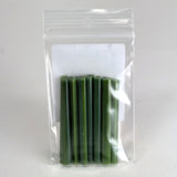 A clear plastic bag containing a group of green, cylindrical objects, which appear to be candles or similar items.