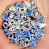 A close-up image of a hand holding a cluster of colorful, heart-shaped objects made of glass or plastic.