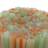 a close-up view of a collection of colorful, translucent tubes or rods, possibly made of glass or a similar material. The tubes have a variety of colors, including shades of green, orange, and white, creating a visually striking and vibrant composition.