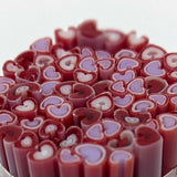 a close-up view of a collection of heart-shaped objects, possibly candies or sweets, with a variety of colors including red, purple, and white.