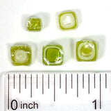 a collection of green and white square beads, with a ruler placed below them to provide a scale reference.