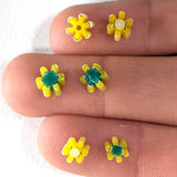 three fingers with small yellow and green flower-shaped objects attached to them.