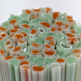 The image is a close-up of a collection of colorful, abstract shapes resembling tubes or pipes, with a mix of green and orange hues.