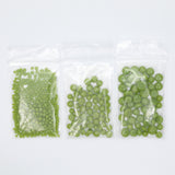 Three clear plastic bags filled with green beads are arranged in a row on a white background.