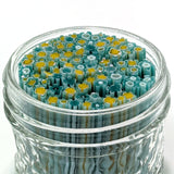 A glass jar filled with colorful glass rods or rods made of blue and yellow glass, creating a visually striking and vibrant display.