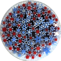 The image is a circular arrangement of various colored glass flowers, including red and blue flowers, creating a visually appealing and vibrant display.