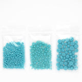 Three transparent plastic bags filled with blue beads are arranged in a row.