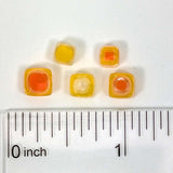 a collection of small, colorful beads arranged on a ruler for size comparison.