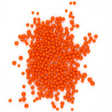a large number of small, round orange beads or spheres scattered across a white background.