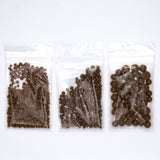 Three transparent plastic bags filled with various sizes of brown objects, such as beads or nuts, are arranged in a row.
