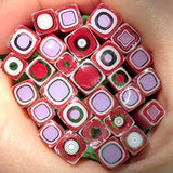 A close-up image of a hand holding a collection of colorful, abstract glass or ceramic pieces with various shapes and patterns, including circles, squares, and other geometric designs.