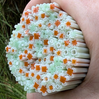 A hand is holding a large cluster of colorful, flower-shaped objects made of plastic or other materials.
