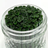 A glass jar filled with green, leaf-shaped objects, possibly candies or decorations.