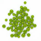 a collection of green pea pods or green beads scattered on a white background.