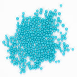 numerous small, round, blue beads scattered across a white background.