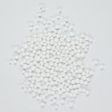 a collection of small white beads or spheres scattered together on a plain background.