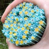 A hand holding a large collection of blue and yellow flower-shaped objects, which appear to be made of a flexible material.