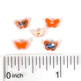 five small, colorful beads arranged on a ruler for size comparison.