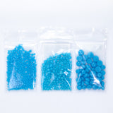 Three transparent plastic bags filled with blue beads are arranged in a row against a white background.