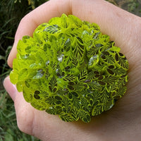 A hand is holding a green leaf-shaped object, which appears to be made of a material that resembles leaves.
