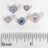 a collection of heart-shaped beads, each varying in size, placed next to a ruler for scale.