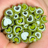 A hand holding a cluster of heart-shaped objects made of green and white materials.
