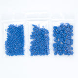 Three clear plastic bags filled with blue beads are arranged in a row.