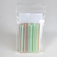 A clear plastic bag containing a collection of colorful straws in various shades of green and orange.
