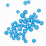 numerous small, round blue beads scattered across a white background.