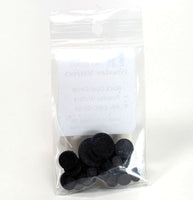 Clear plastic bag with black circular Powder Wafers inside on a white background