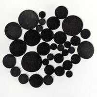 The contents of one bag of fusible black Powder Wafer Circles various sizes on a white background