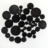 The contents of one bag of fusible black Powder Wafer Circles various sizes on a white background