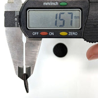 Digital caliper measuring a black object with a white background reading 1.57mm in thickness