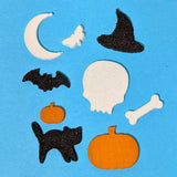 Set of Halloween-themed cutouts including a moon, bat, witch hat, skull, pumpkin, and black cat on a blue background.
