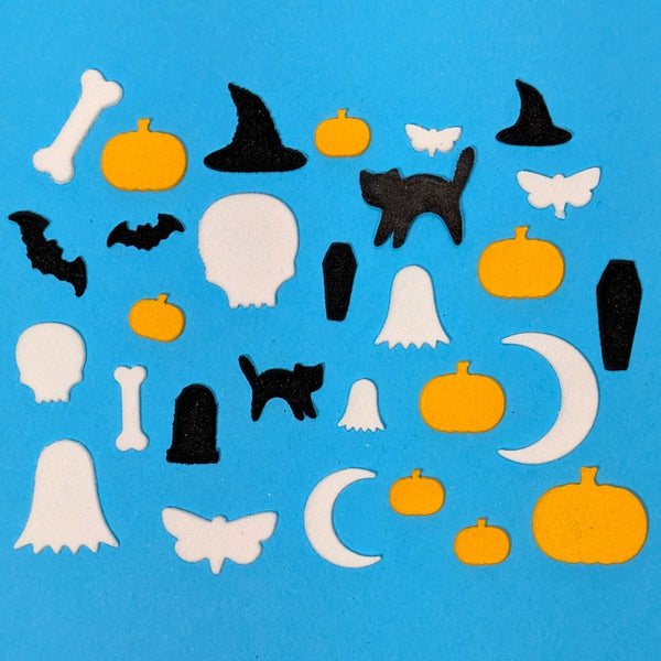 Collection of Halloween-themed cutouts including pumpkins, ghosts, cats, and bats on a blue background.